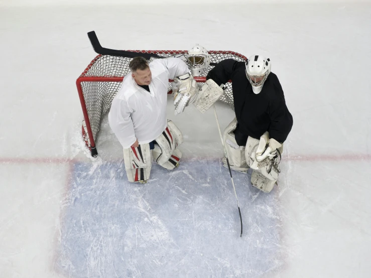 a couple of men standing next to each other on a hockey field, inspired by John Gibson, ap, top - down photograph, ap news photograph, white