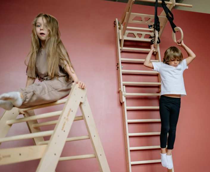 a little girl sitting on top of a wooden ladder, by Nina Hamnett, trending on pexels, figuration libre, in a gym, boy and girl, two hang, closed limbo room