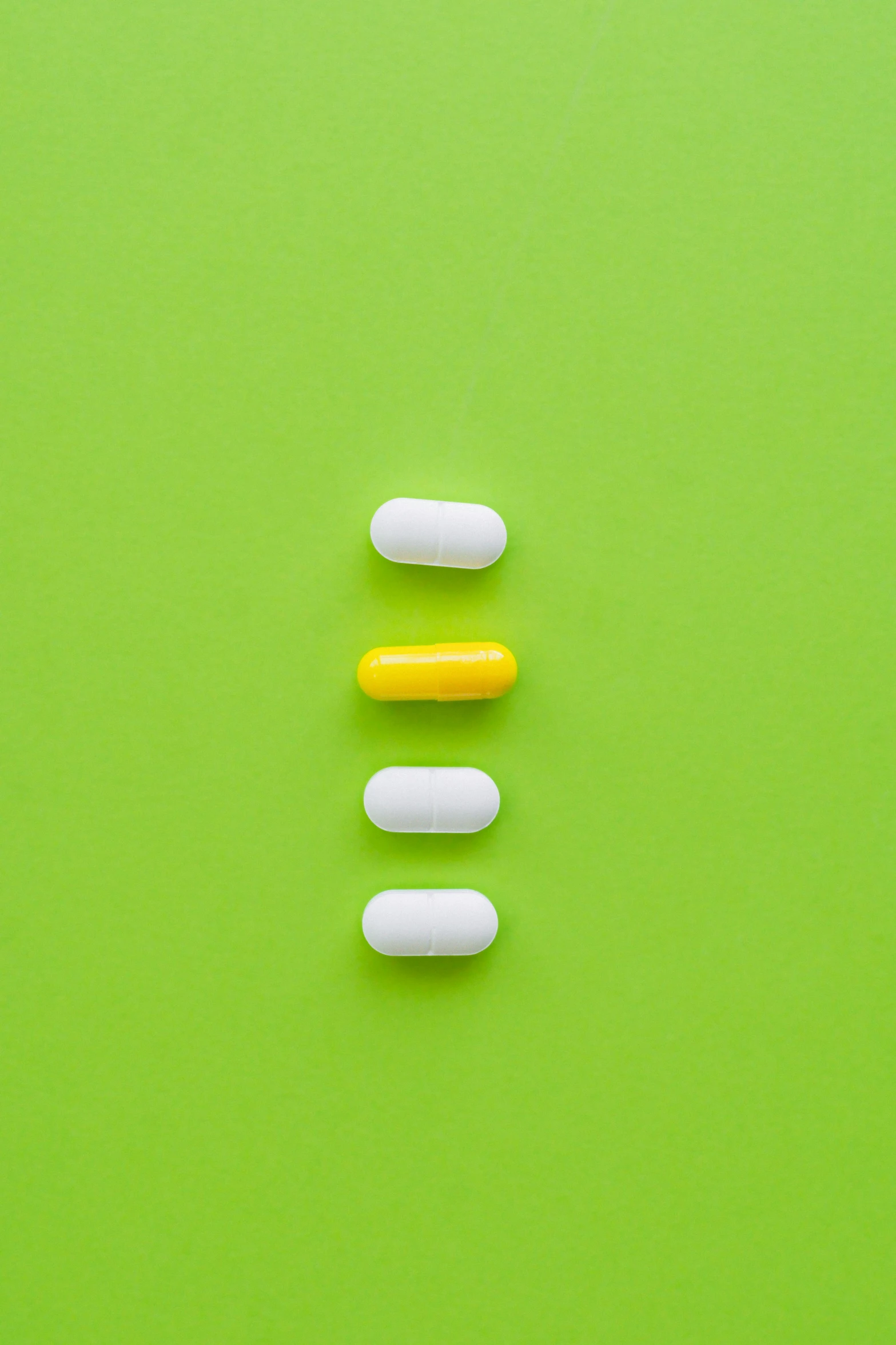 three white and yellow pills on a green background, by Adam Chmielowski, antipodeans, lined up horizontally, q, medium shoot, 4 colors