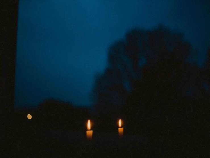 a couple of candles sitting on top of a window sill, an album cover, unsplash, visual art, float under moon light at night, at the graveyard at midnight, overcast bokeh, moonlight through trees