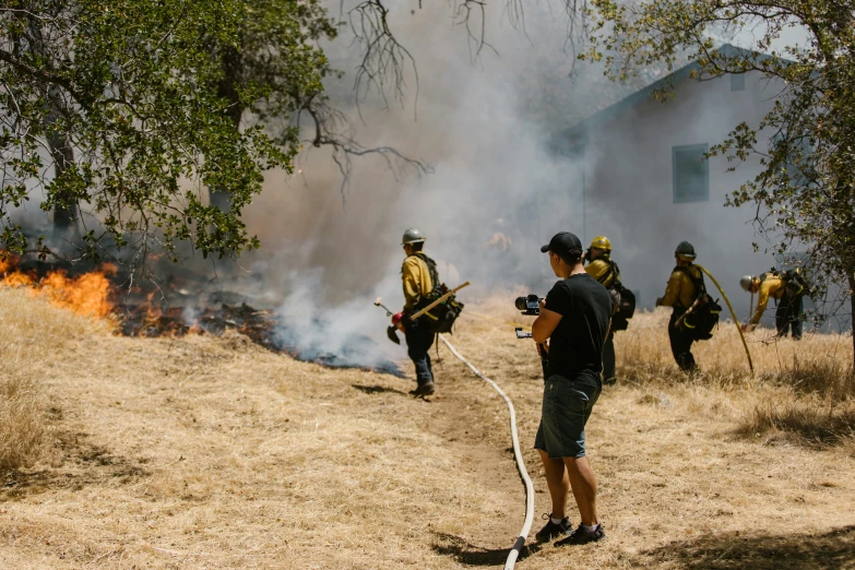 a group of men standing on top of a grass covered hillside, by William Berra, pexels contest winner, house on fire, firefighter, avatar image, california;