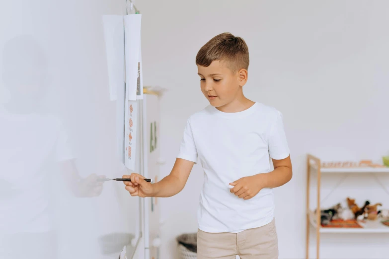 a young boy standing in front of a white refrigerator, a child's drawing, pexels contest winner, interactive art, holding a paintbrush in his hand, wearing a white shirt, gif, wall painting