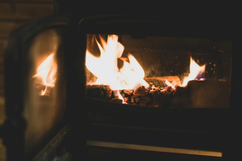 a close up of a fire in a stove, pexels contest winner, winter setting, background image, facing sideways, cozy aesthetic