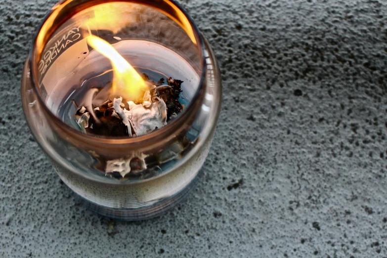 a close up of a lit candle on a table, smoking outside, bird's eye view, fire punch, molten glass