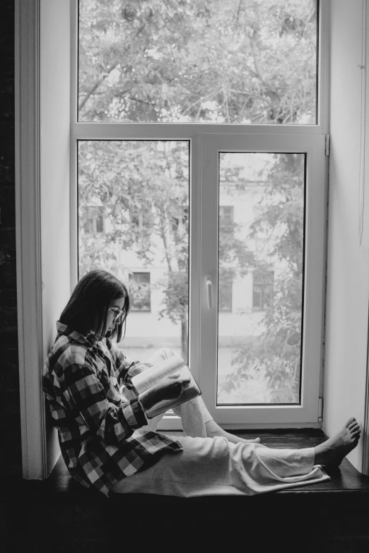 a woman sitting on a window sill reading a book, a black and white photo, inspired by Elsa Bleda, unsplash contest winner, aestheticism, фото девушка курит, casual pose, boy staring at the window, teenage girl