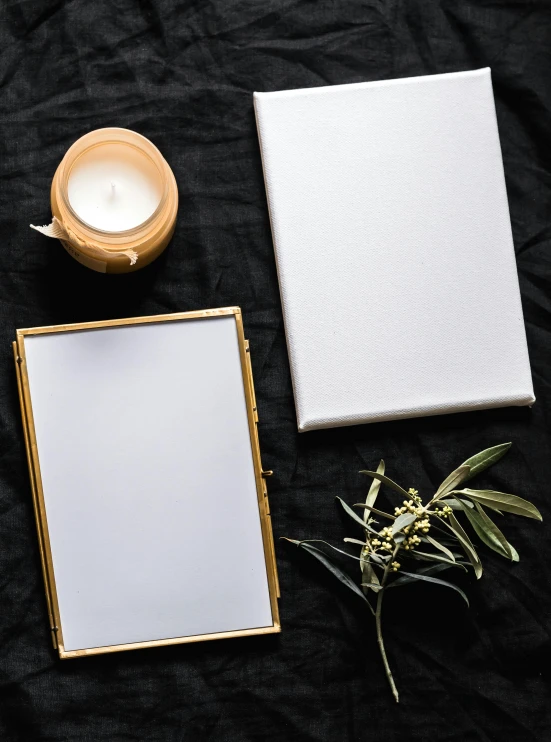 a cup of coffee sitting on top of a table next to a book, a minimalist painting, inspired by Eden Box, trending on unsplash, gold and white robes, square pictureframes, candlelit, gray canvas