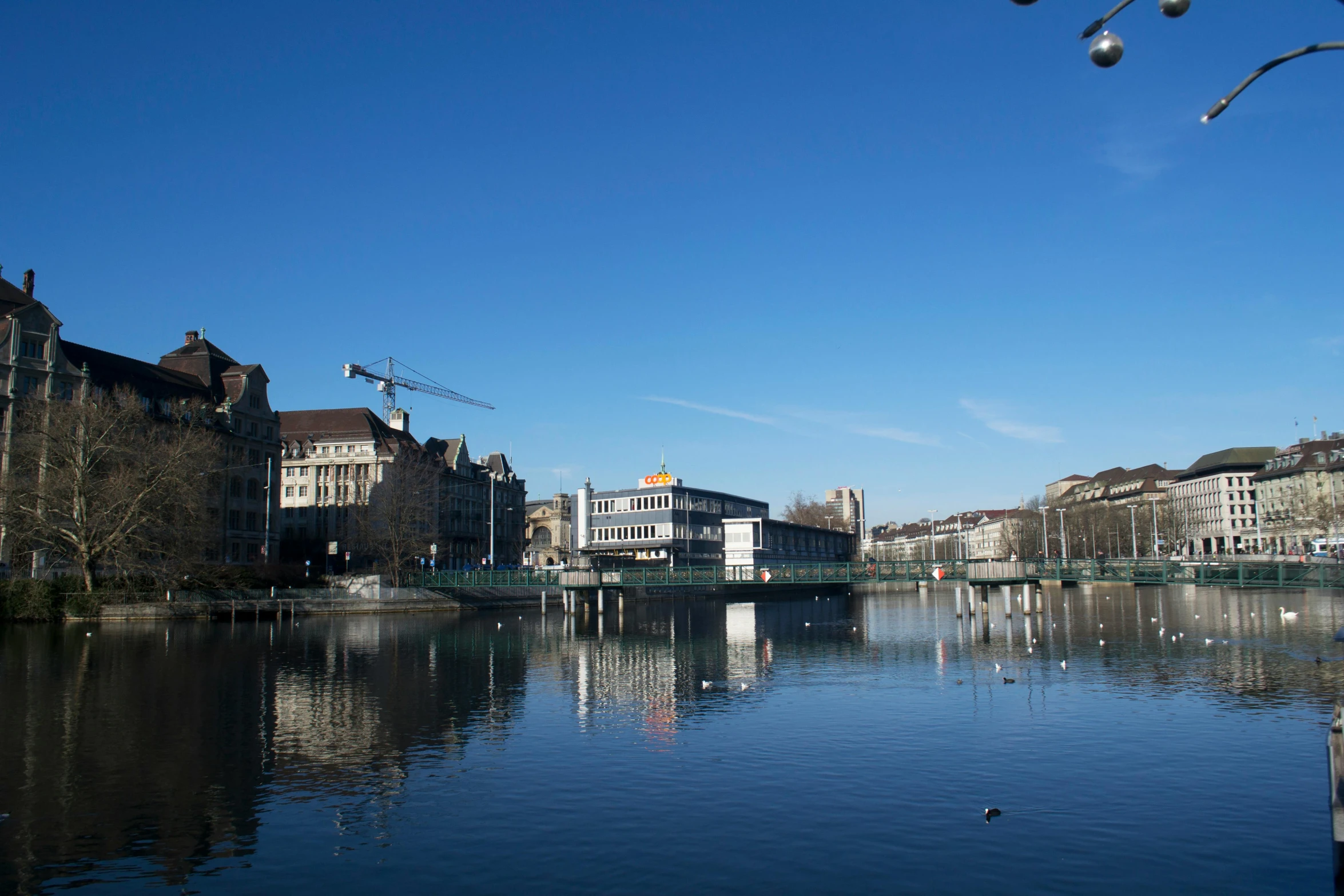 a body of water with buildings in the background, swiss architecture, 2022 photograph, clear blue skies, thumbnail