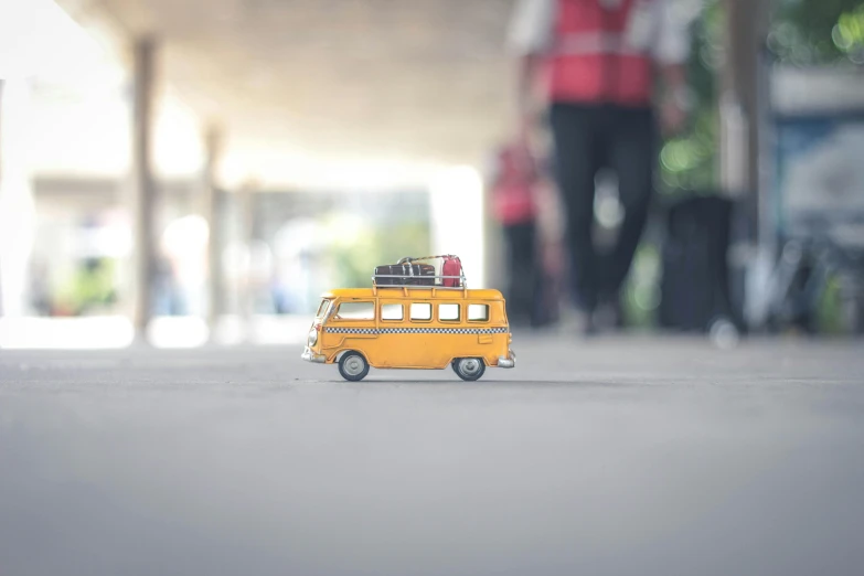 a toy bus with luggage on top of it, a tilt shift photo, inspired by Wes Anderson, pexels contest winner, on the concrete ground, van, student, ilustration