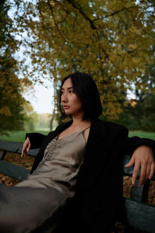 a woman sitting on a bench in a park, an album cover, inspired by Jung Park, unsplash, realism, maggie cheung, modelling, autum, photographed for reuters