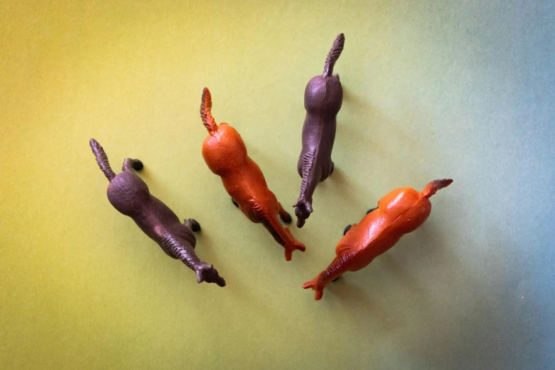 a group of toy animals laying on top of a table, an album cover, inspired by Bruce Nauman, unsplash, figuration libre, carrots, purple orange colors, 3/4 view from below, lizard legs