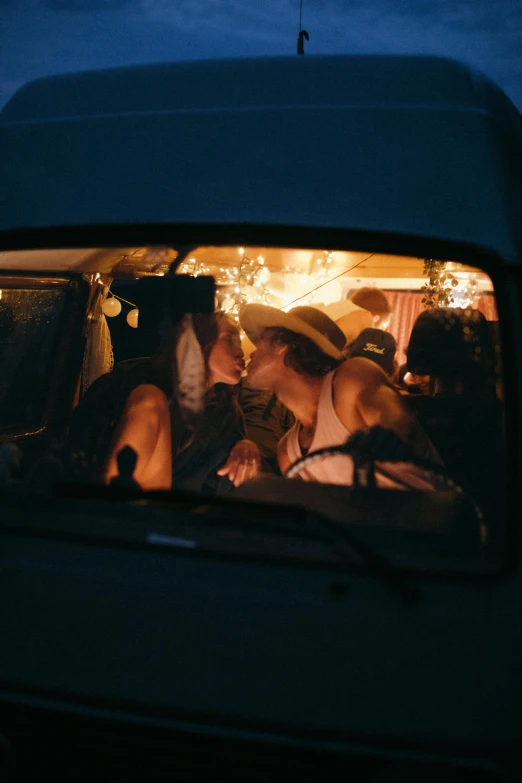 a group of people sitting in the back of a van, by Jessie Algie, unsplash contest winner, romanticism, portrait of two girls kissing, long night cap, holiday season, 256435456k film