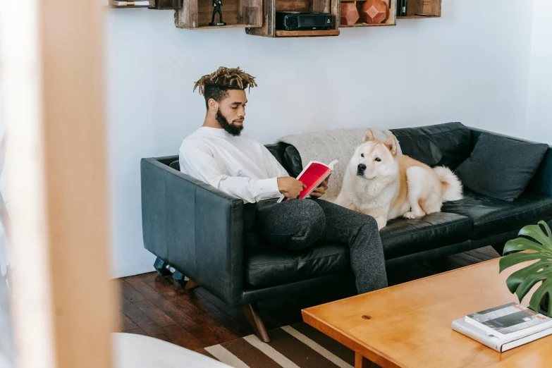 a man sitting on a couch with a dog, pexels contest winner, black man, reading for a party, 1450, real trending on instagram image