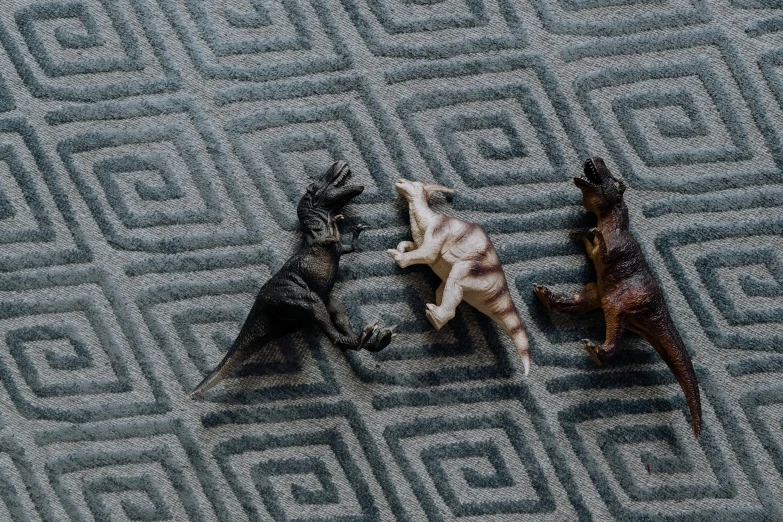 a couple of toy animals laying on top of a rug, by Carey Morris, pexels contest winner, velociraptor, leading a battle, panels, three animals