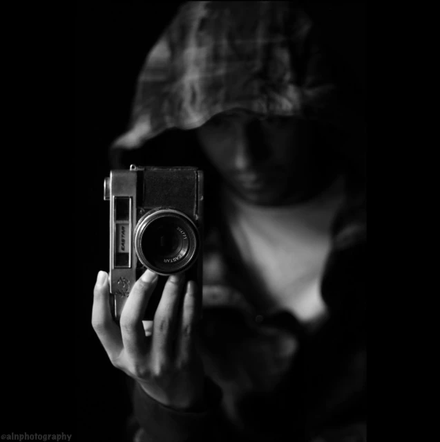 a black and white photo of a person holding a camera, a black and white photo, by Adam Marczyński, art photography, in a black hoodie, by :5 sexy: 7, low quality, eyelevel!!! view!!! photography