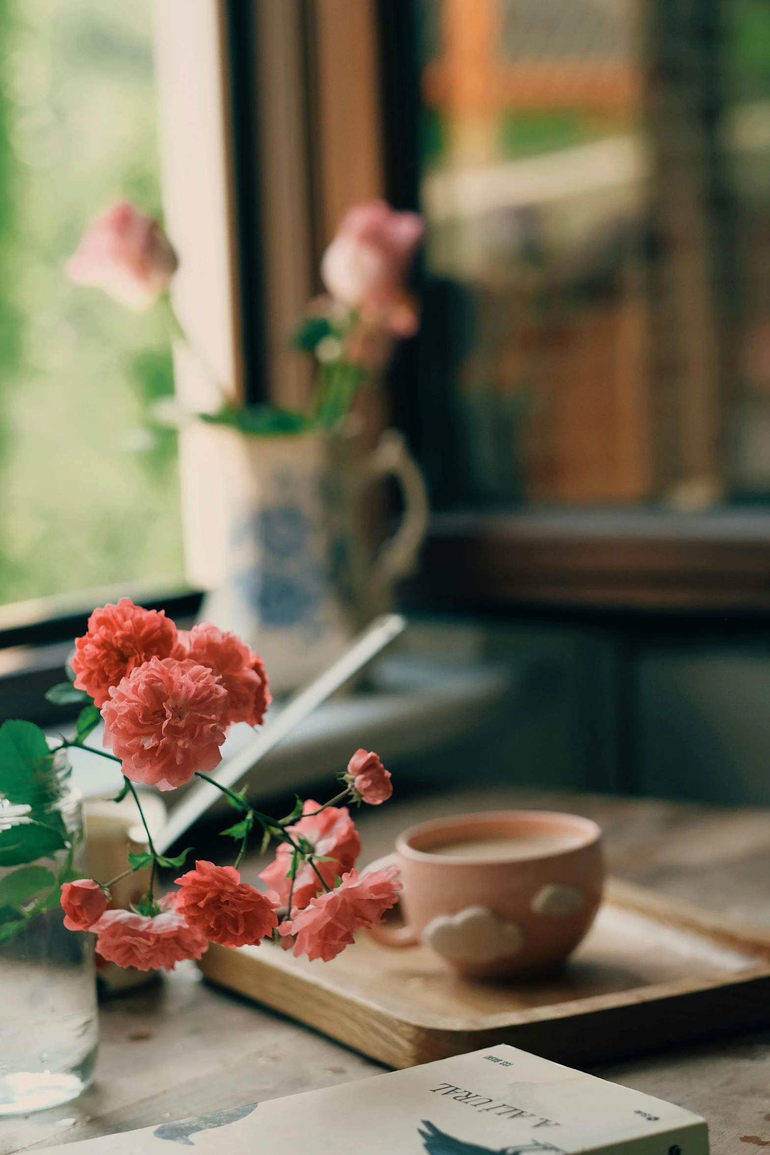 a book sitting on top of a wooden table next to a cup of coffee, a still life, by Anna Boch, trending on unsplash, romanticism, japanese flower arrangements, photo of a beautiful window, soft light 4 k in pink, red flowers