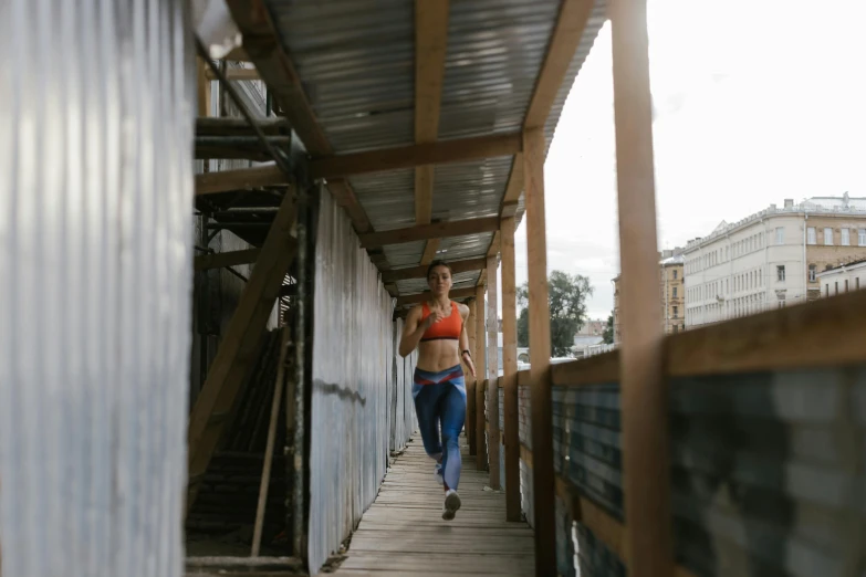 a woman is running on a wooden walkway, azamat khairov, in an alley, sweat and labour, commercial photo