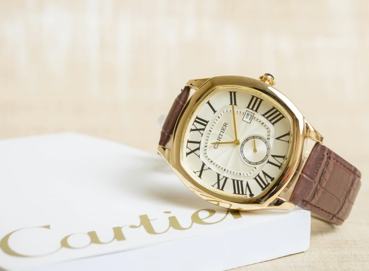 a watch sitting on top of a book, an album cover, inspired by Barthélemy Menn, instagram, relaxed. gold background, cartier, catalog photo, ivory