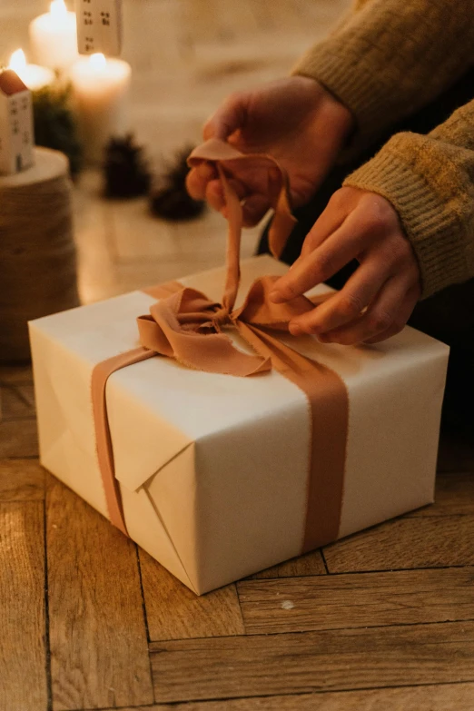 a person tying a ribbon on a wrapped present, happening, beige, [ organic, uplit, customers