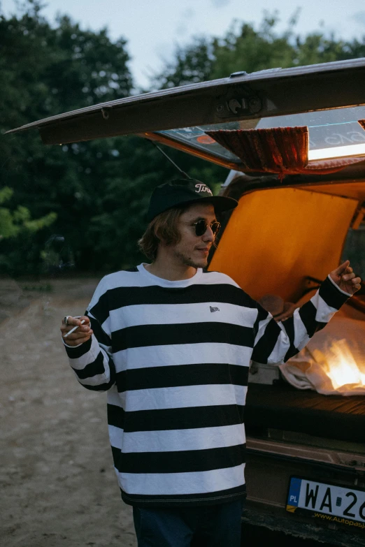 a man standing next to a fire in the back of a truck, unsplash, striped shirt, ready to eat, beret and sunglasses, jc park