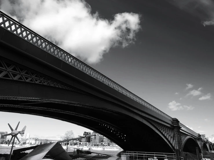 a black and white photo of a bridge over a river, a black and white photo, inspired by Thomas Häfner, unsplash, london south bank, low angle!!!!, beautiful day, detailed medium format photo