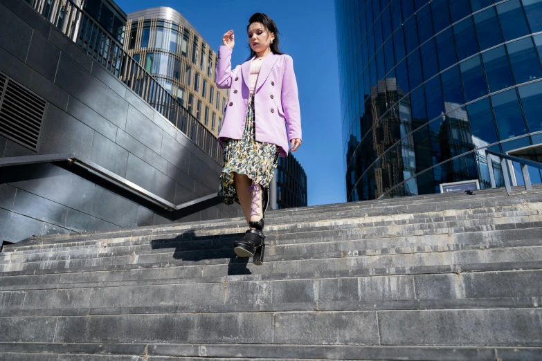 a woman is walking up a flight of stairs, by Julia Pishtar, a purple suit jacket, wearing jacket and skirt, on a sunny day, ameera al taweel