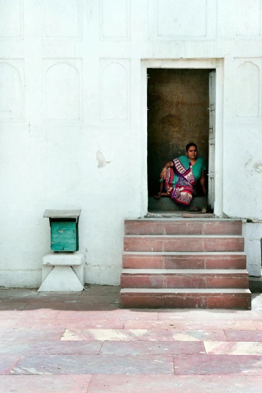 a woman sitting in a doorway of a building, indian style, in a square, taken in the late 2010s, fan favorite