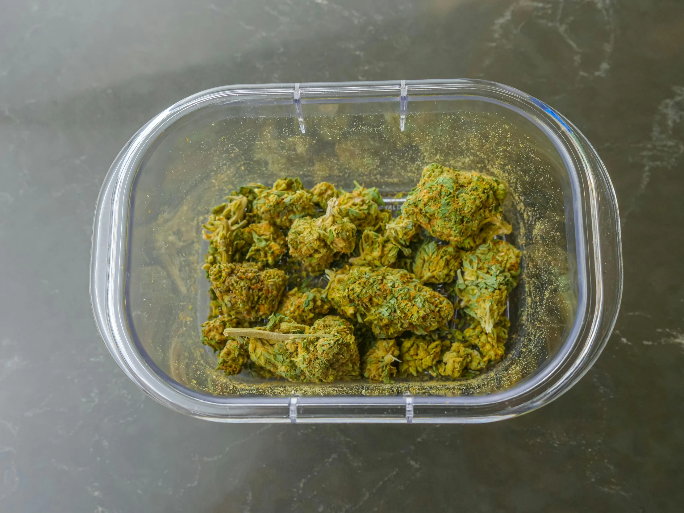 a container filled with marijuana buds on top of a table, lush green, nugget, in plastic, top down angle