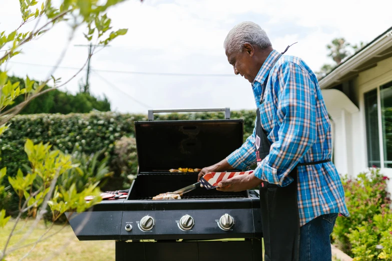 a man preparing food on a grill outside, essence, patriotic, fan favorite, an elderly