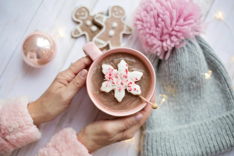 a close up of a person holding a cup of hot chocolate, by Julia Pishtar, seven pointed pink star, gingerbread people, food styling, rose gold