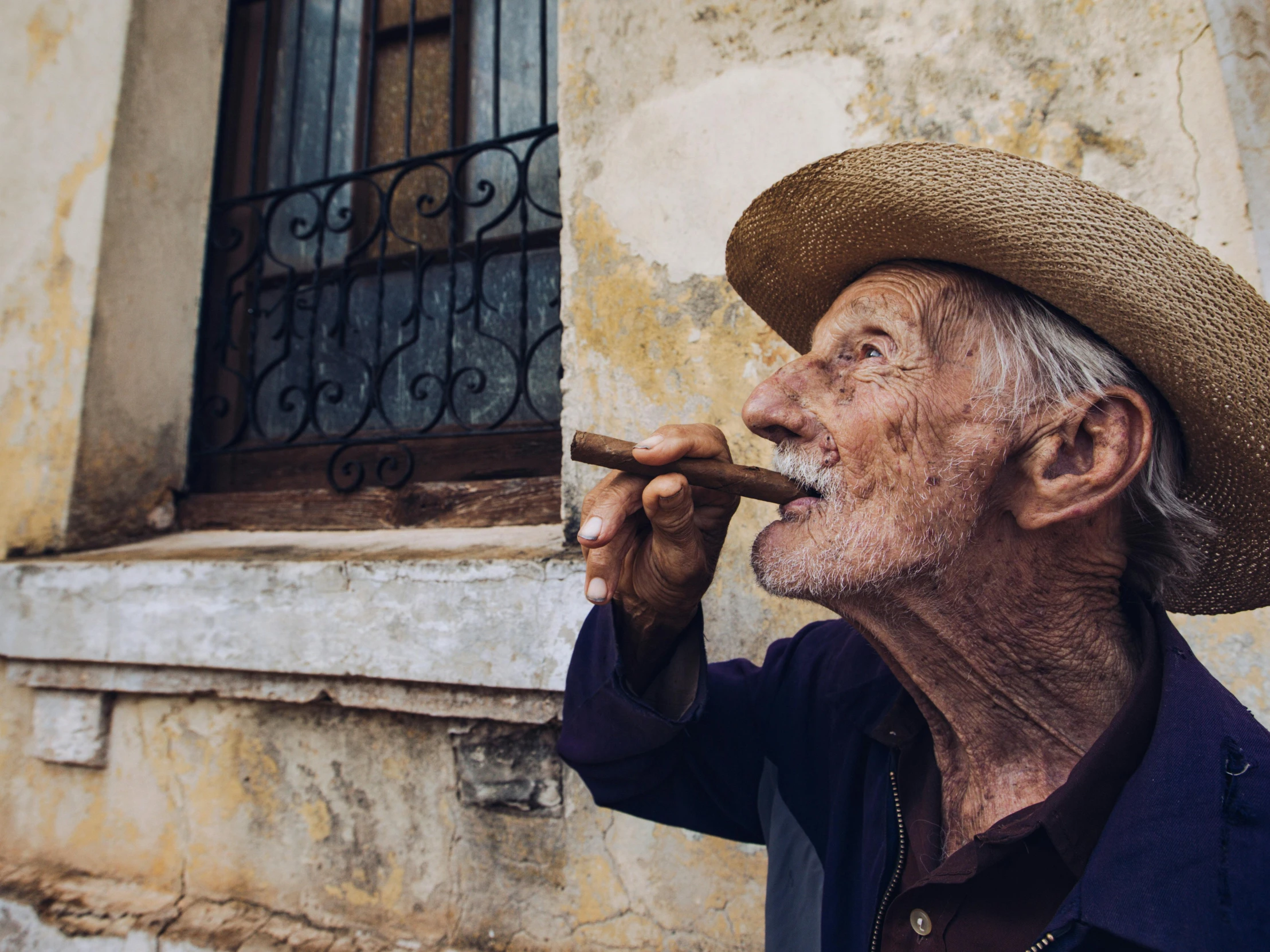 a man in a straw hat smokes a cigar, by Will Ellis, pexels contest winner, hyperrealism, very old, cuban setting, profile image, tiny smokes from buildings