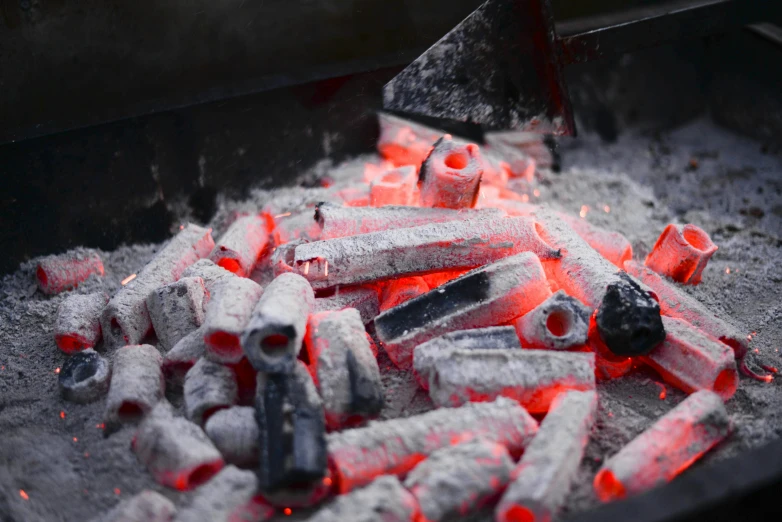 a pile of coal sitting on top of a grill, flares, barbecuing chewing gum, grey, warm coloured