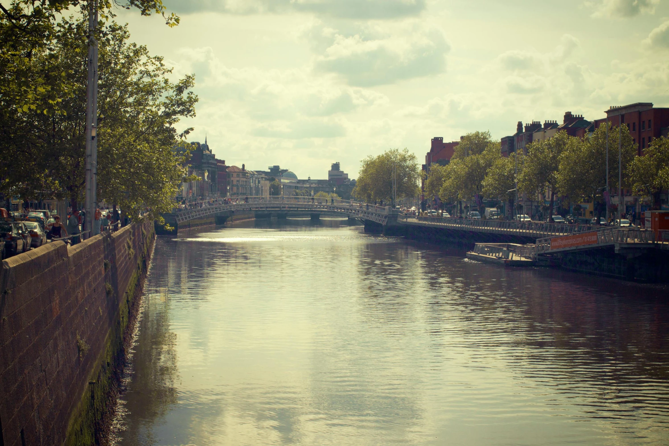 a river running through a city next to tall buildings, a photo, inspired by Eamon Everall, happening, retro style ”, ireland, a photo of a lake on a sunny day, canals