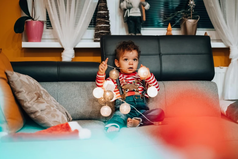 a little boy that is sitting on a couch, by Julia Pishtar, pexels contest winner, happening, decorated ornaments, string lights, 2 years old, 15081959 21121991 01012000 4k