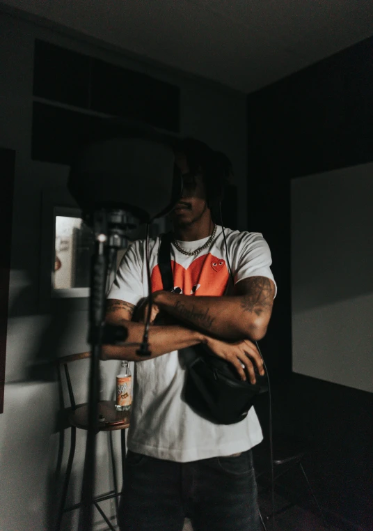 a man standing in a room holding a frisbee, an album cover, trending on pexels, realism, travis scott, in a dark studio room, looking serious, low quality video