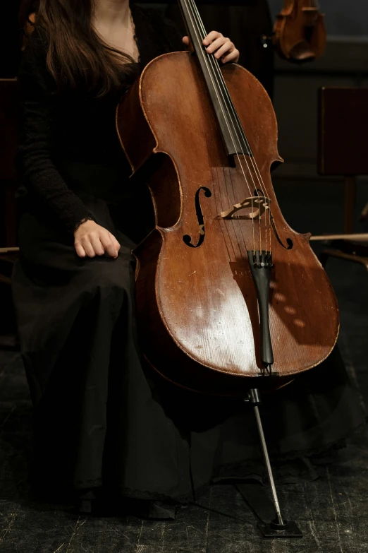 a woman sitting on a chair holding a cello, unsplash, baroque, rectangle, low detail, worn, extremely polished