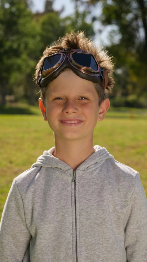 a little boy that is standing in the grass, by Arnie Swekel, photorealism, sport glasses, brown, high quality photo, thumbnail