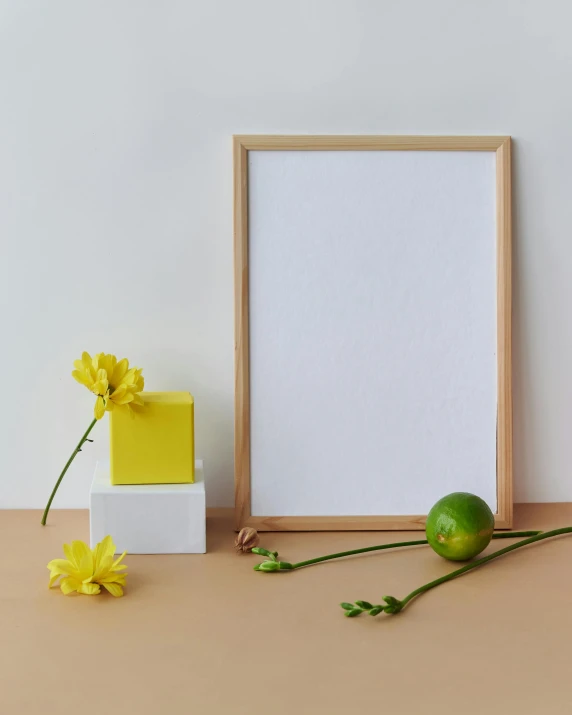 a picture frame sitting on top of a table next to a flower, inspired by Robert Mapplethorpe, lemon, solid colours material, product introduction photo, white box