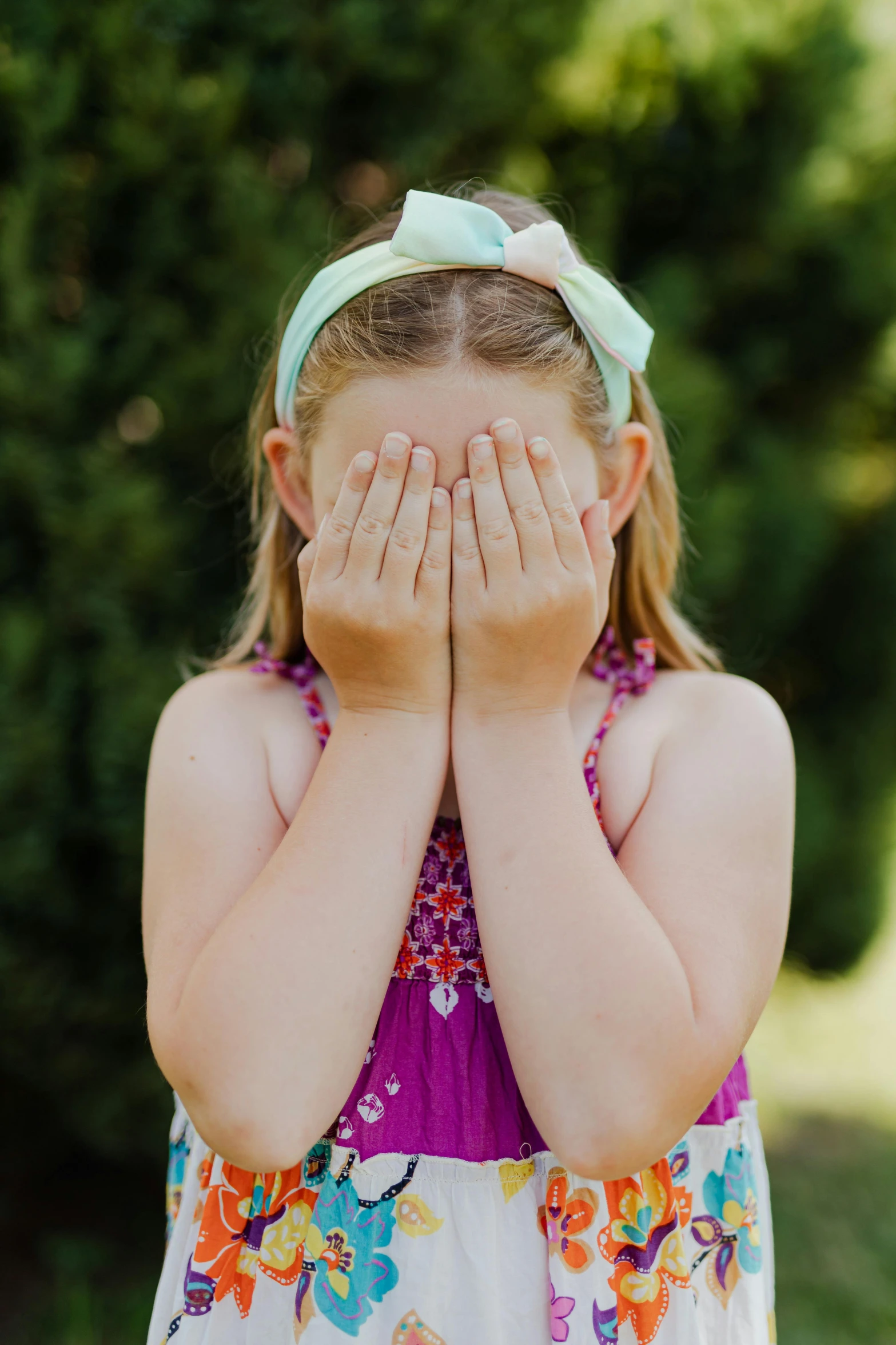 a little girl covering her face with her hands, wearing hair bow, face shown, embarrassing, hidden message