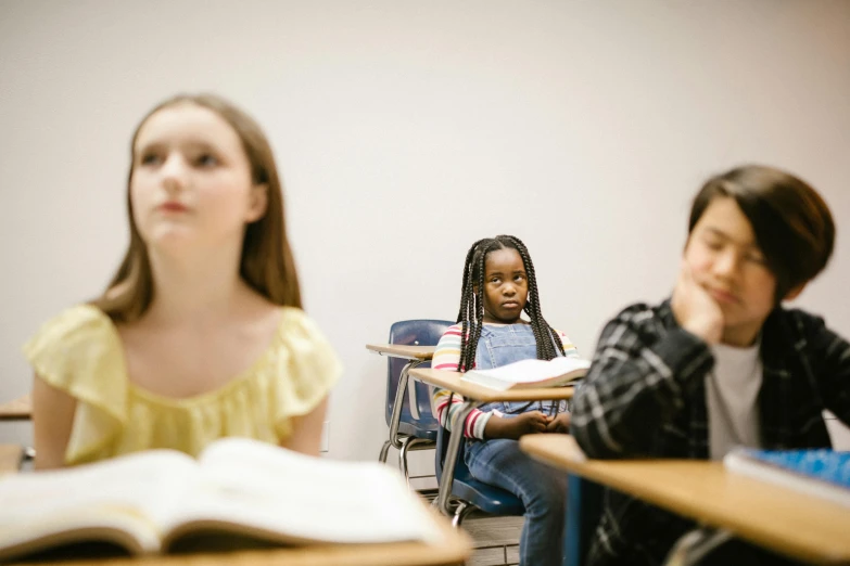 a group of children sitting at desks in a classroom, by Adam Chmielowski, trending on unsplash, hyperrealism, tiny girl looking on, looking serious, 2000s photo