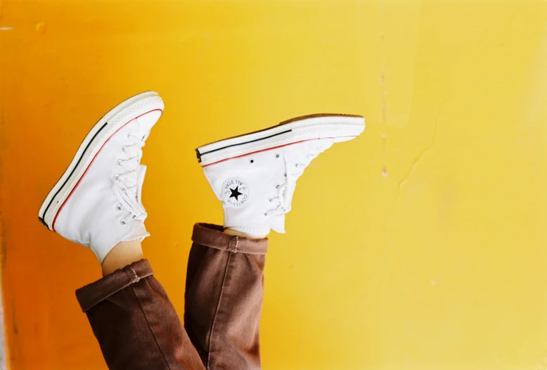 a person's feet in a pair of brown boots, trending on pexels, photorealism, white and yellow scheme, converse, yellow backdrop, white and orange