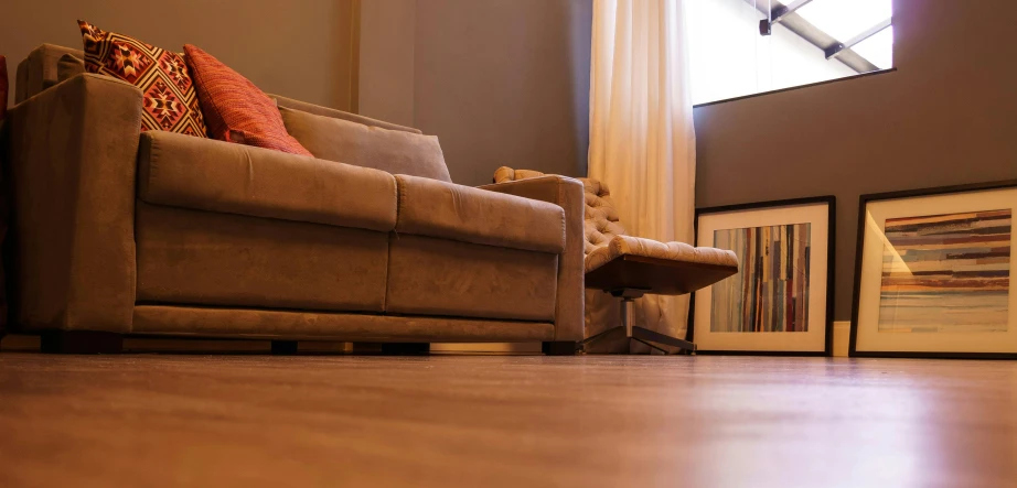 a couch sitting in a living room next to a window, unsplash, hyperrealism, hardwood floor, close - up photograph, reclining, brown