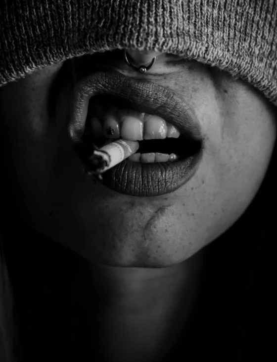 a woman with a cigarette in her mouth, a black and white photo, by Adam Marczyński, pexels contest winner, hyperrealism, personification of marijuana, broken teeth, girl wearing hoodie, photo of a black woman