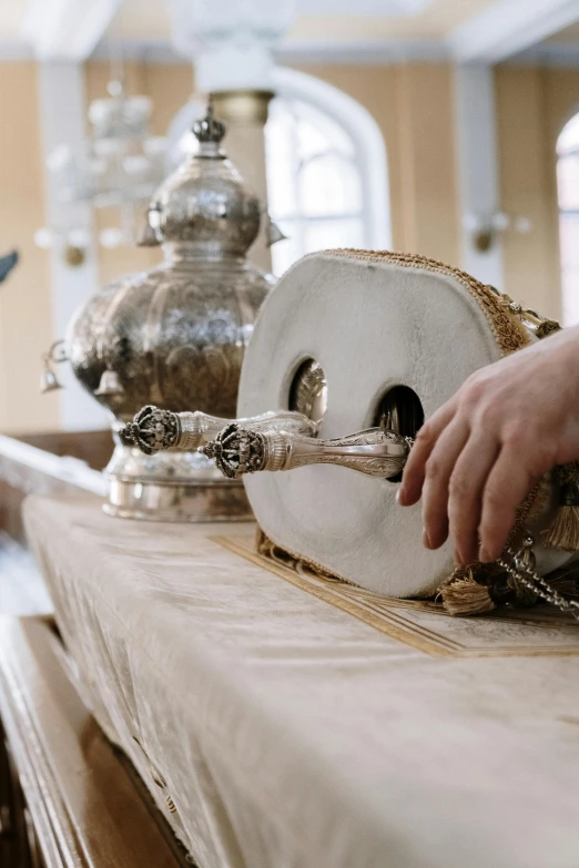 a person cutting a piece of wood on top of a table, arabesque, holding a bell, on the altar, piping, 2019 trending photo