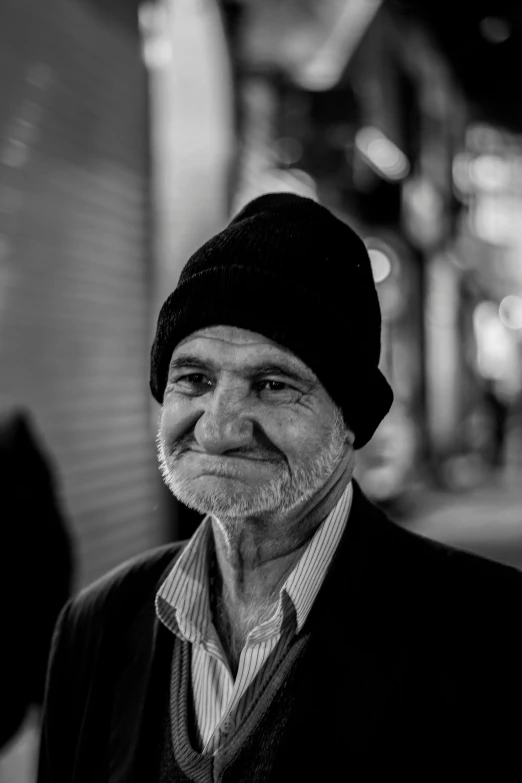 a black and white photo of a man wearing a hat, a black and white photo, pexels contest winner, skilled homeless, almost smiling, a man wearing a black jacket, slightly pixelated