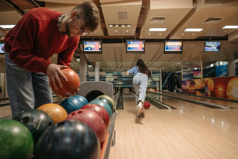 a man playing a game of bowling in a bowling alley, by Zofia Stryjenska, pexels contest winner, interactive art, фото девушка курит, 8k quality, male and female, from the elbow