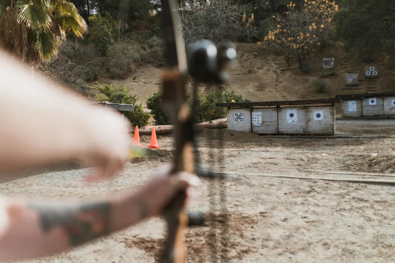 a close up of a person holding a bow, from the distance, shooting, bottom shot, middle of the day