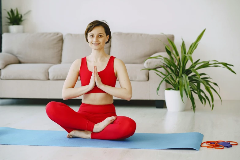 a woman sitting on a yoga mat in a living room, pexels contest winner, hurufiyya, red sport clothing, avatar image, high definition image, proportional image