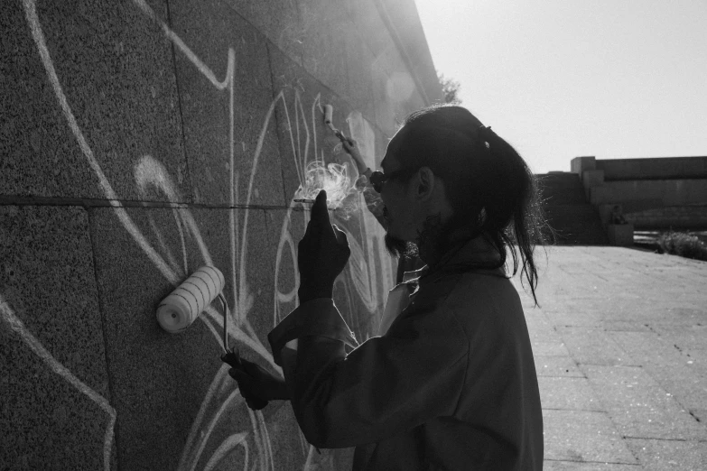 a black and white photo of a woman painting on a wall, graffiti, warm sunshine, 15081959 21121991 01012000 4k, instagram photo, student