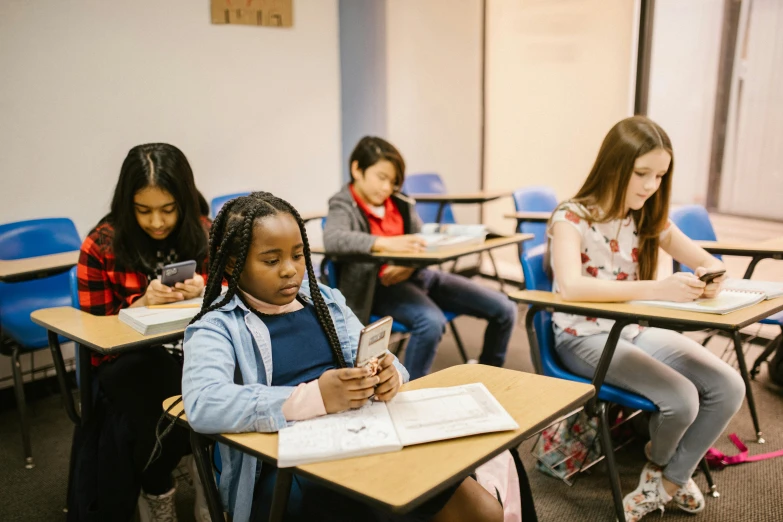 a group of young girls sitting at desks in a classroom, by Meredith Dillman, trending on pexels, she is holding a smartphone, scholarly, thumbnail, diverse