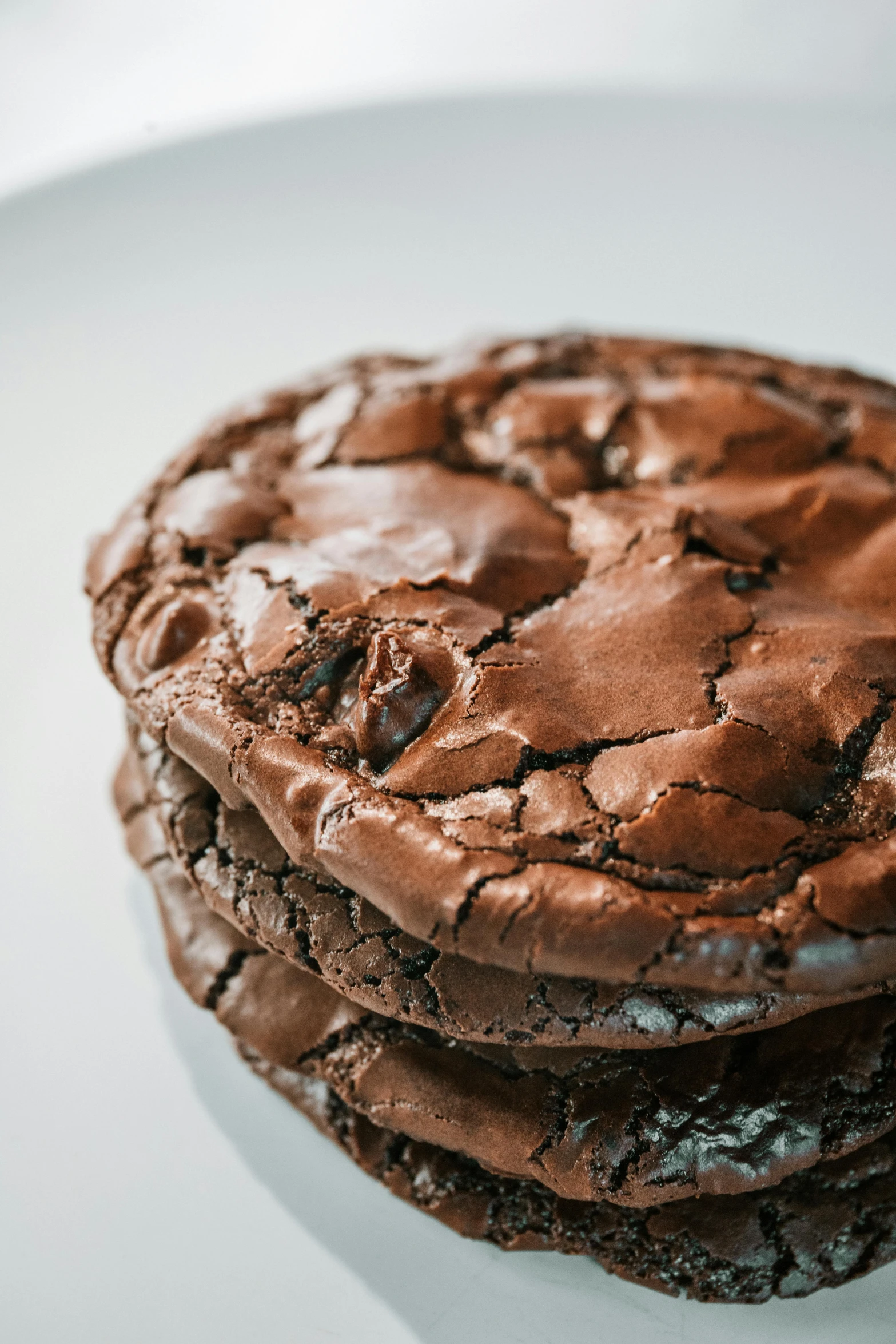 a stack of chocolate cookies sitting on top of a white plate, a portrait, unsplash, art nouveau, rocky roads, 3/4 side view, very sweaty, large cracks